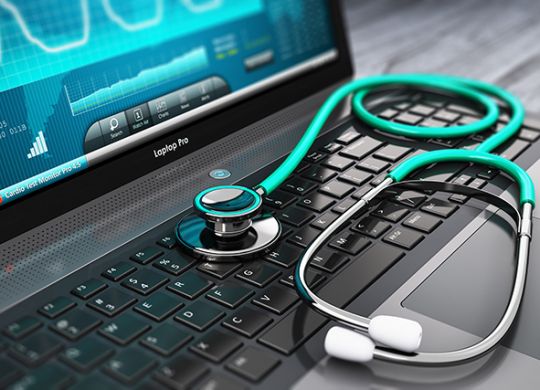 Creative abstract healthcare, medicine and cardiology tool concept: laptop or notebook computer PC with medical cardiologic diagnostic test software on screen and stethoscope on black wooden business office table with selective focus effect
