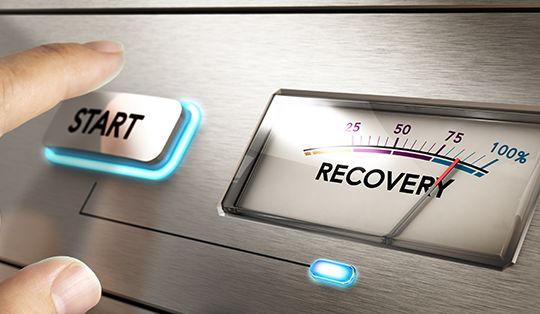 Finger about to press a start button with a dial where it is written the word recovery. Concept image for illustration of crisis or disaster recovery plan.